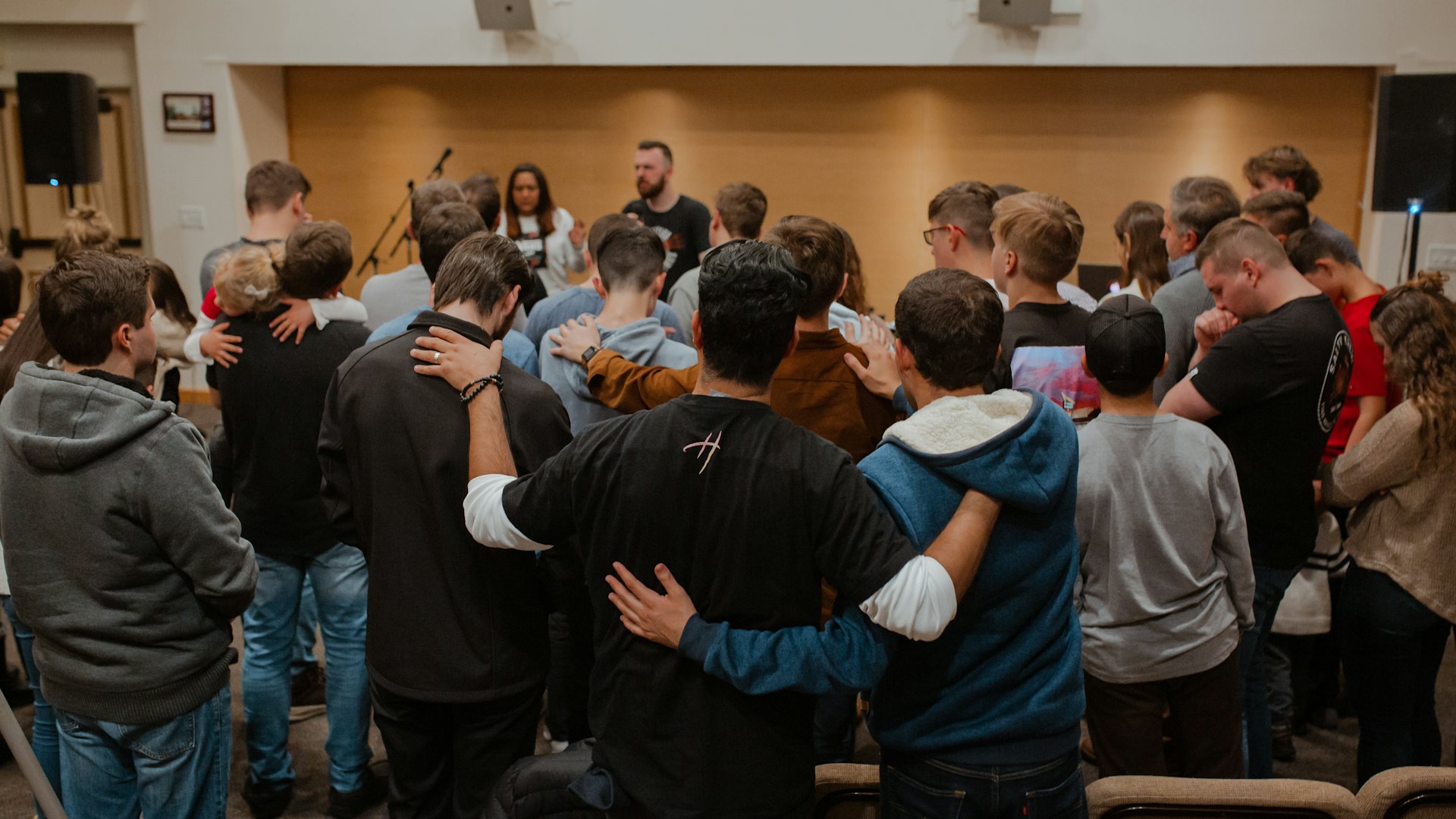 A group of people standing in a circle with their arms around each other's shoulders